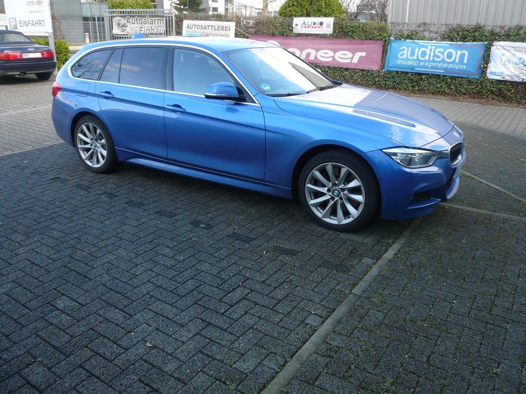 Ein blaues Auto steht vor einem Schild mit der Aufschrift „Audison“