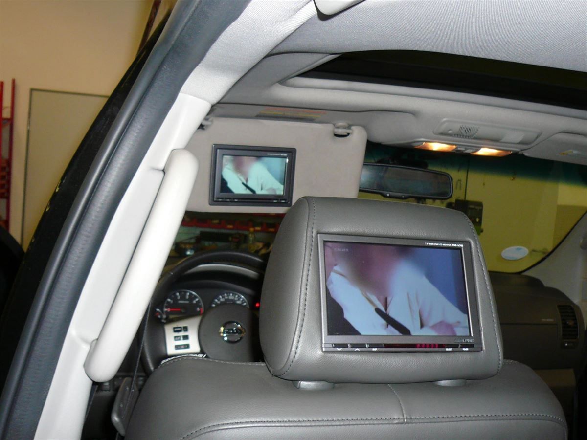 Alpine TME-M780 17,8 cm (7-Zoll) Kopfstützen-Monitor in die Original Nissan Pathfinder Kopfstütze eingearbeitet. TME-M680 14,7 cm (5,8-Zoll) Monitor in die Sonnenblende vom Nissan Pathfinder eingearbeitet. Alpine DVB-T2 TV-Tuner montiert.
