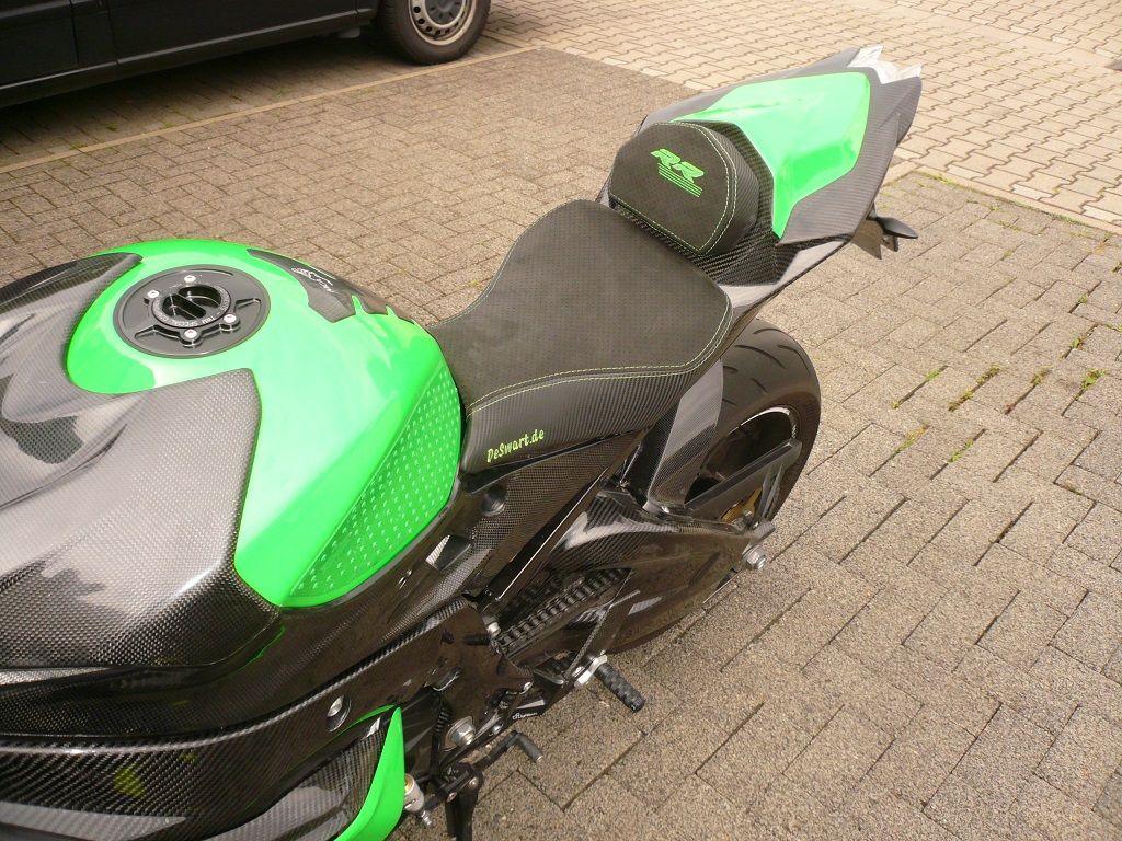 Ein schwarz-grünes Motorrad ist auf einem gepflasterten Gehweg geparkt