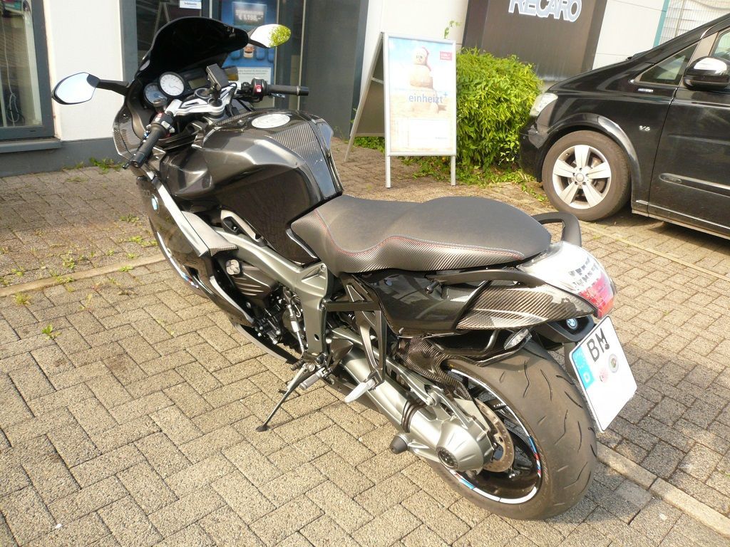 Ein schwarzes Motorrad ist auf einer gepflasterten Auffahrt geparkt