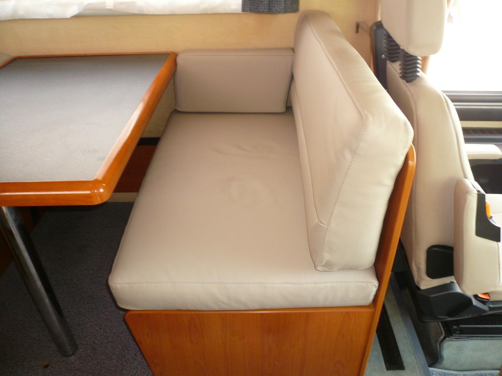 Eine Couch mit einem weißen Kissen steht neben einem Tisch