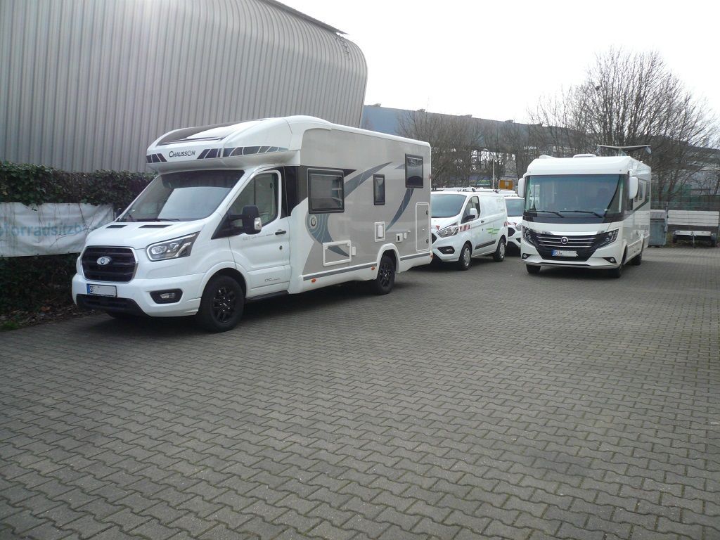 Eine Reihe weißer Wohnmobile steht auf einem Parkplatz.