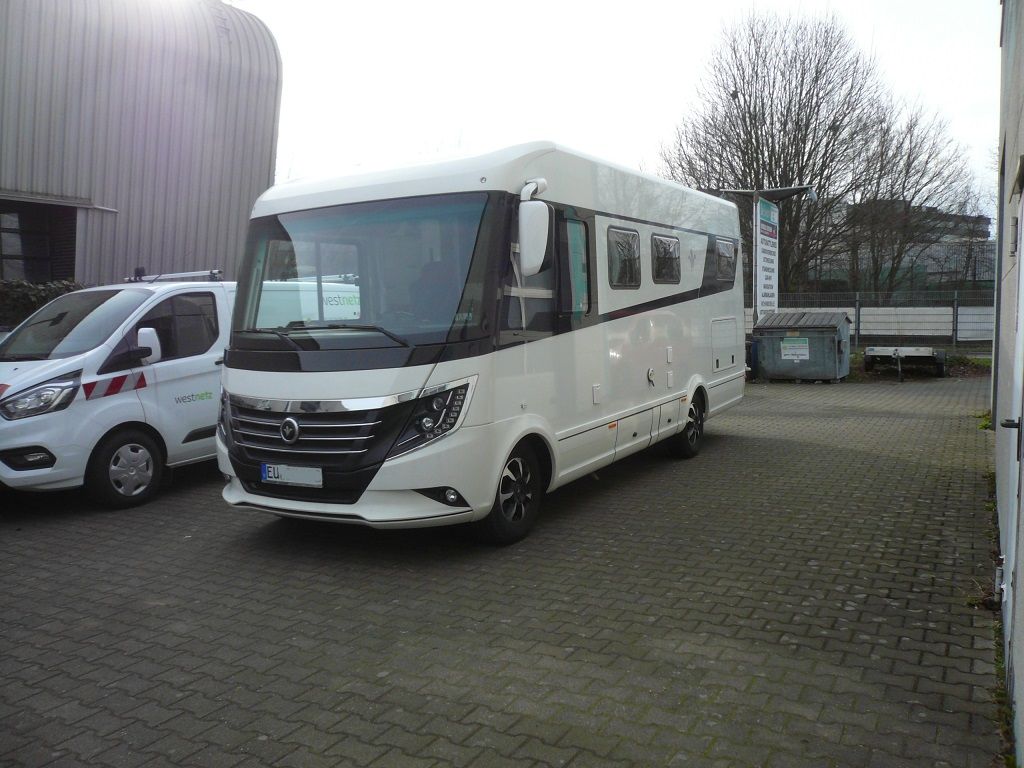 Ein großes weißes Wohnmobil steht auf einem Parkplatz