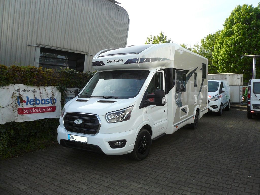 Ein weißes Wohnmobil steht vor einem Webasto-Schild