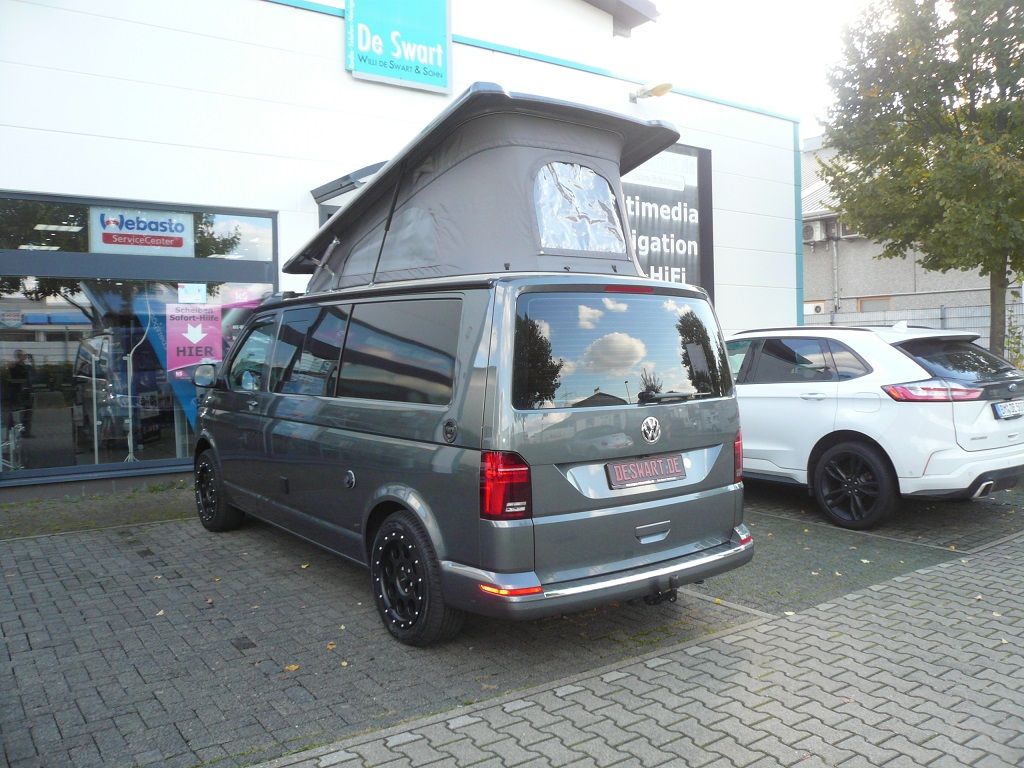 Ein Lieferwagen mit Aufstelldach steht vor einem Geschäft