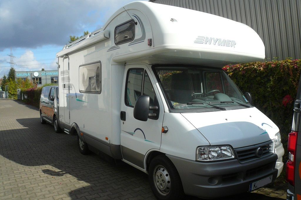 Ein weißes Wohnmobil steht vor einem Gebäude