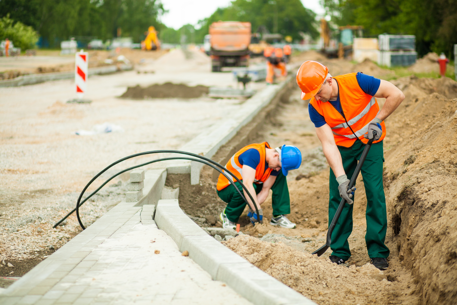 Zwei Bauarbeiter arbeiten auf einer Straßenbaustelle.