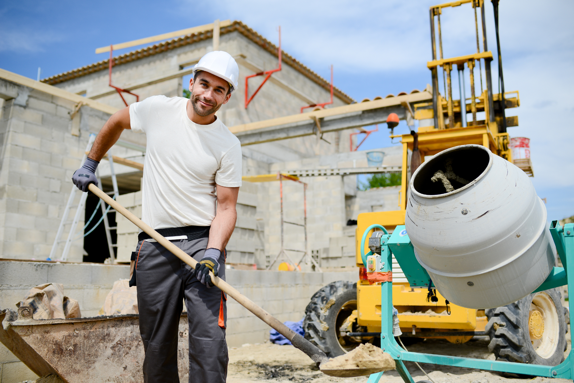 Ein Bauarbeiter steht auf einer Baustelle neben einem Betonmischer.
