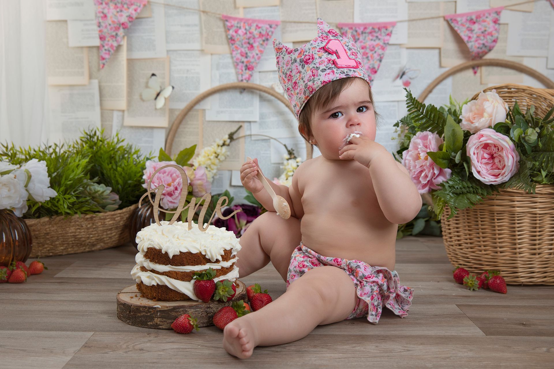 Una niña está sentada en el suelo comiendo un pastel.