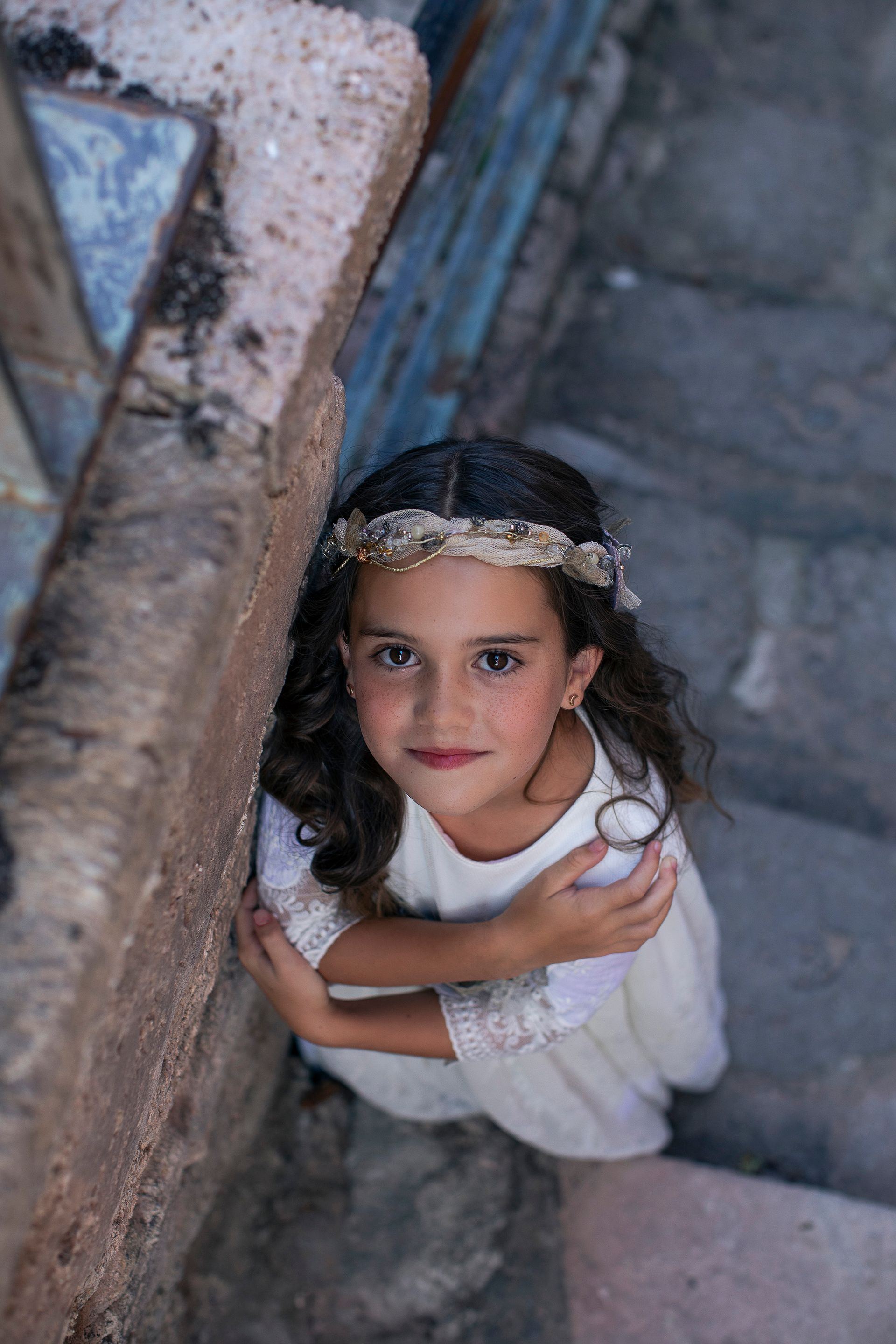 Una niña con un vestido blanco está sentada en unas escaleras.