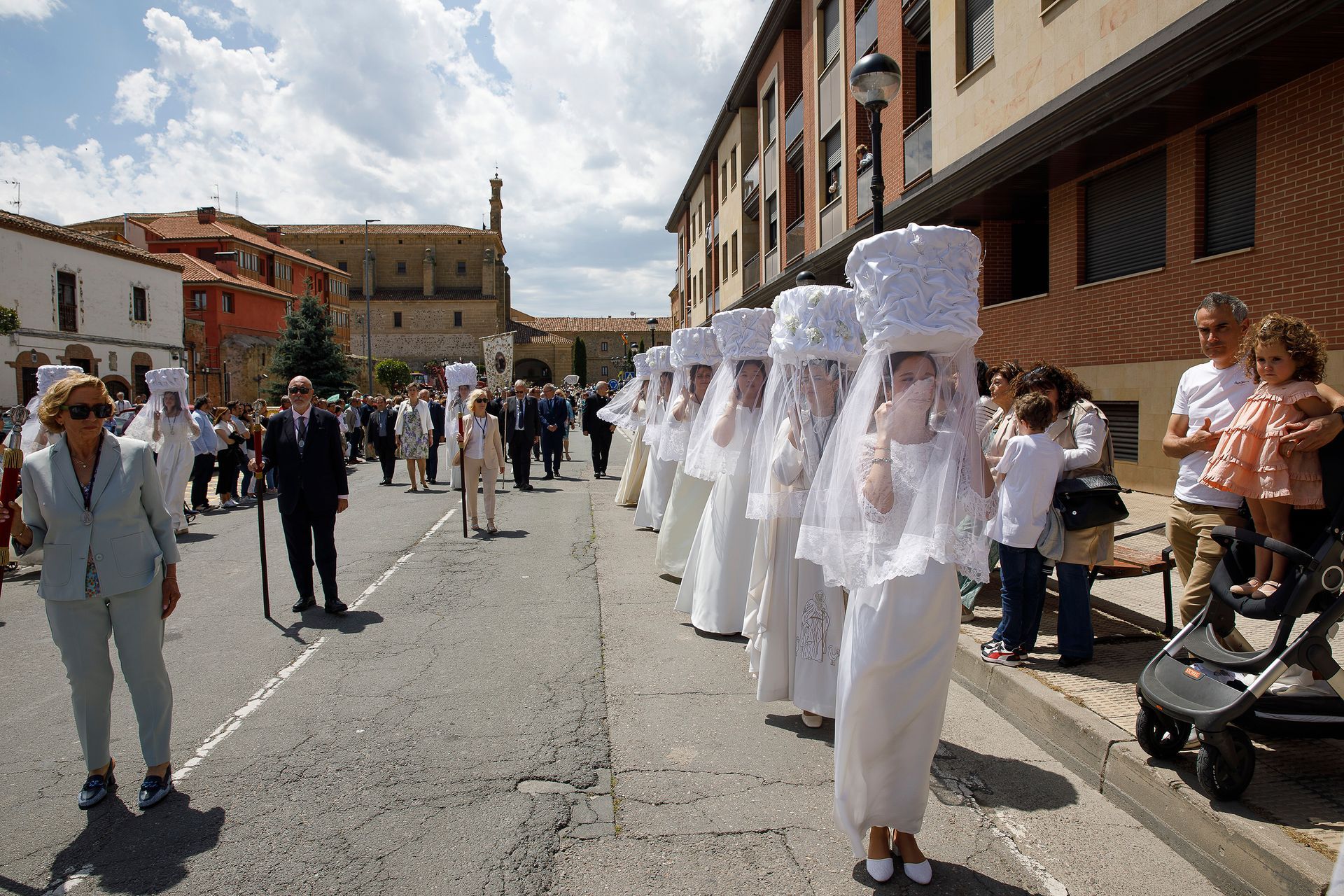 Un grupo de personas vestidas de blanco caminan por una calle.