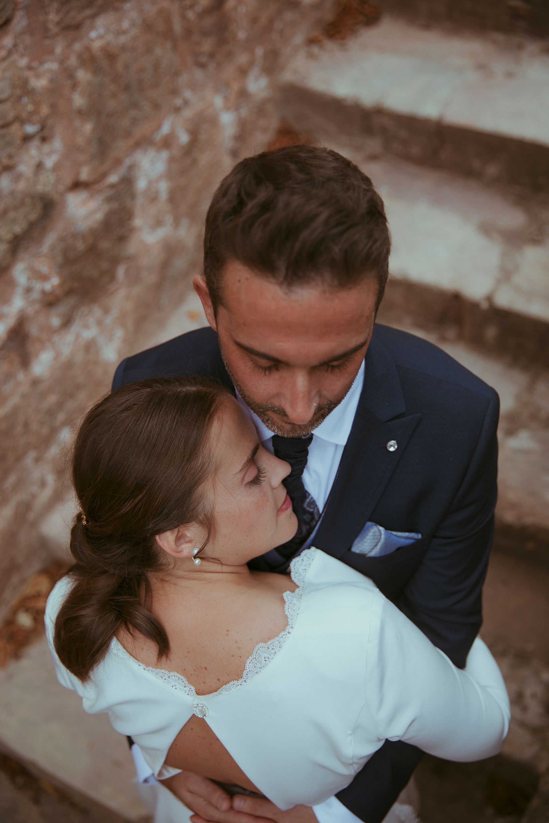 Una novia y un novio se abrazan en unas escaleras.
