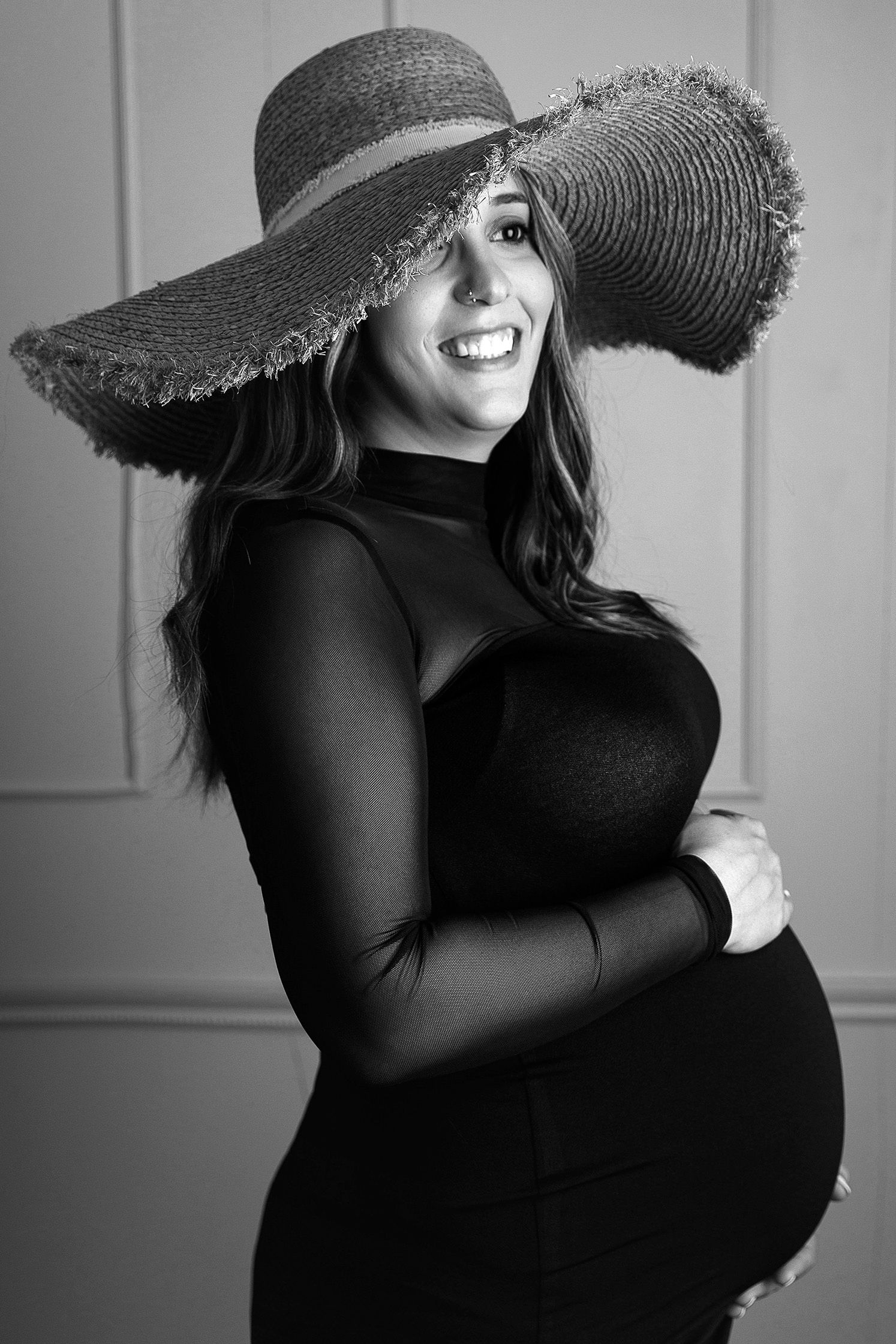 Una fotografía en blanco y negro de una mujer embarazada con sombrero.