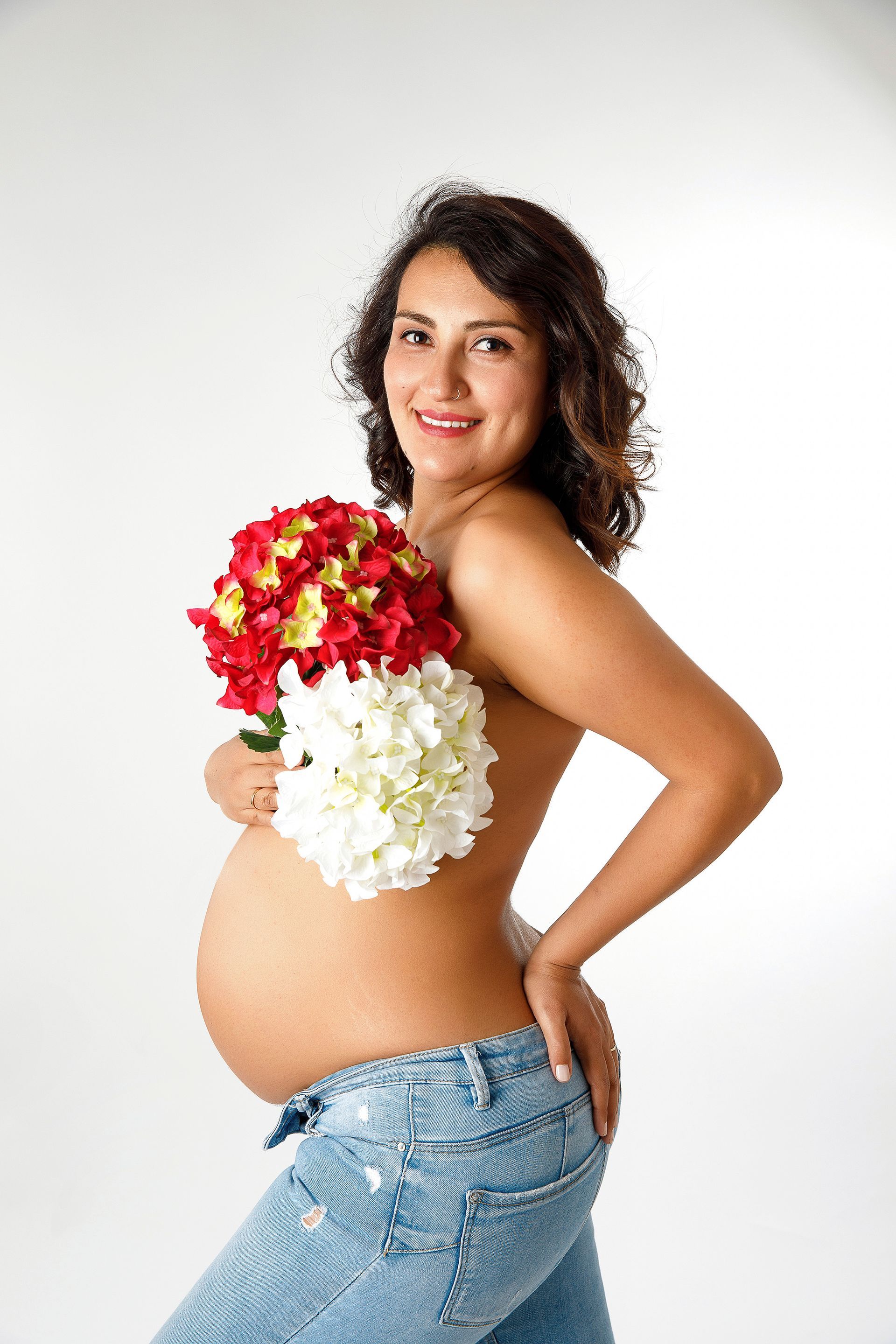 Una mujer embarazada sostiene un ramo de flores.