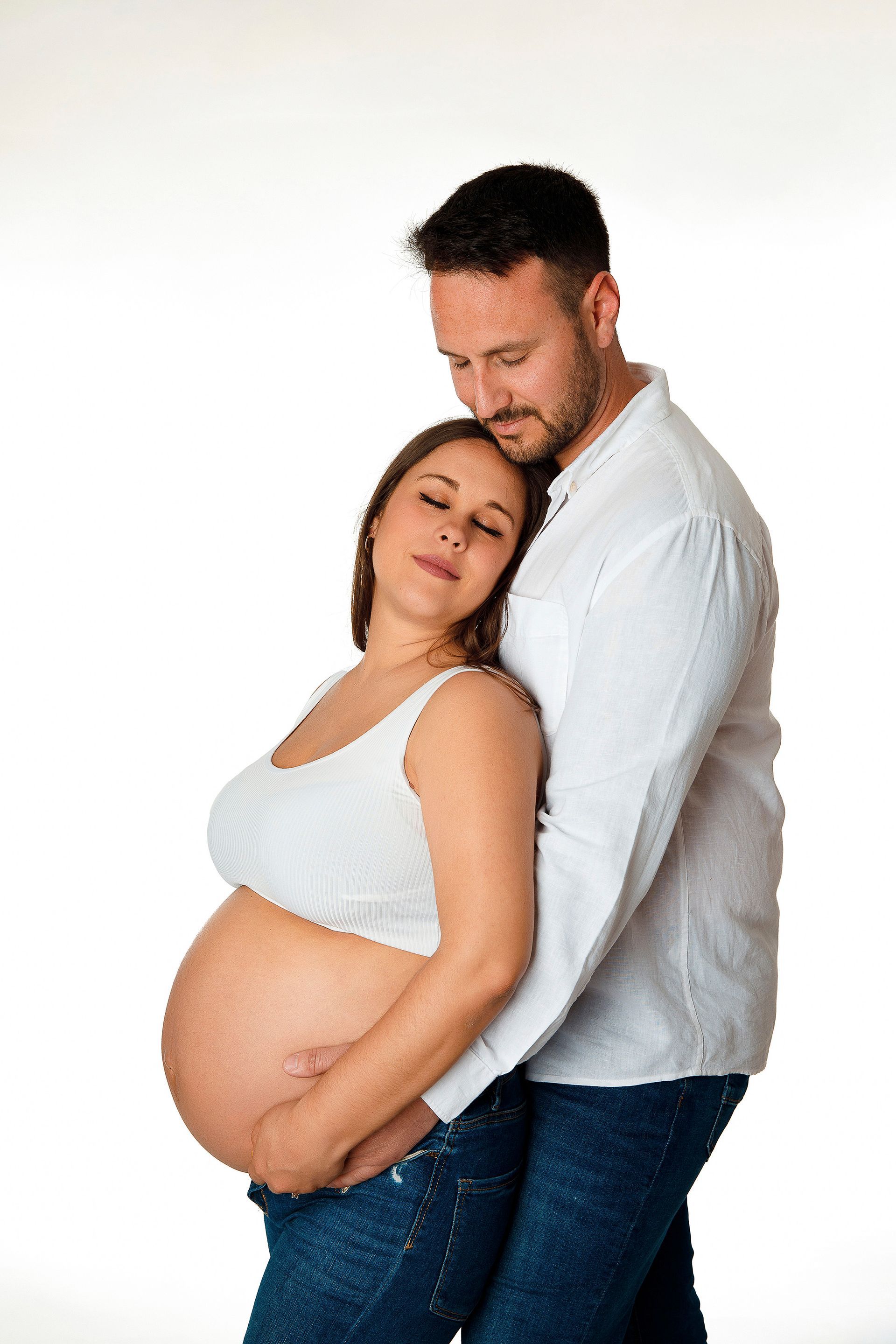 Un hombre y una mujer embarazada se abrazan.
