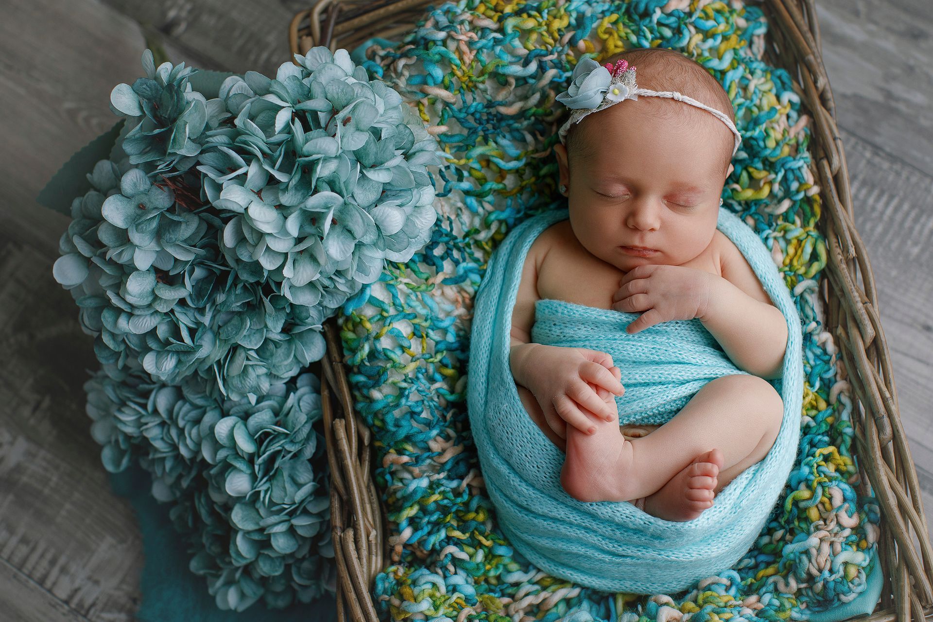 Un bebé recién nacido envuelto en una manta azul duerme en una canasta.