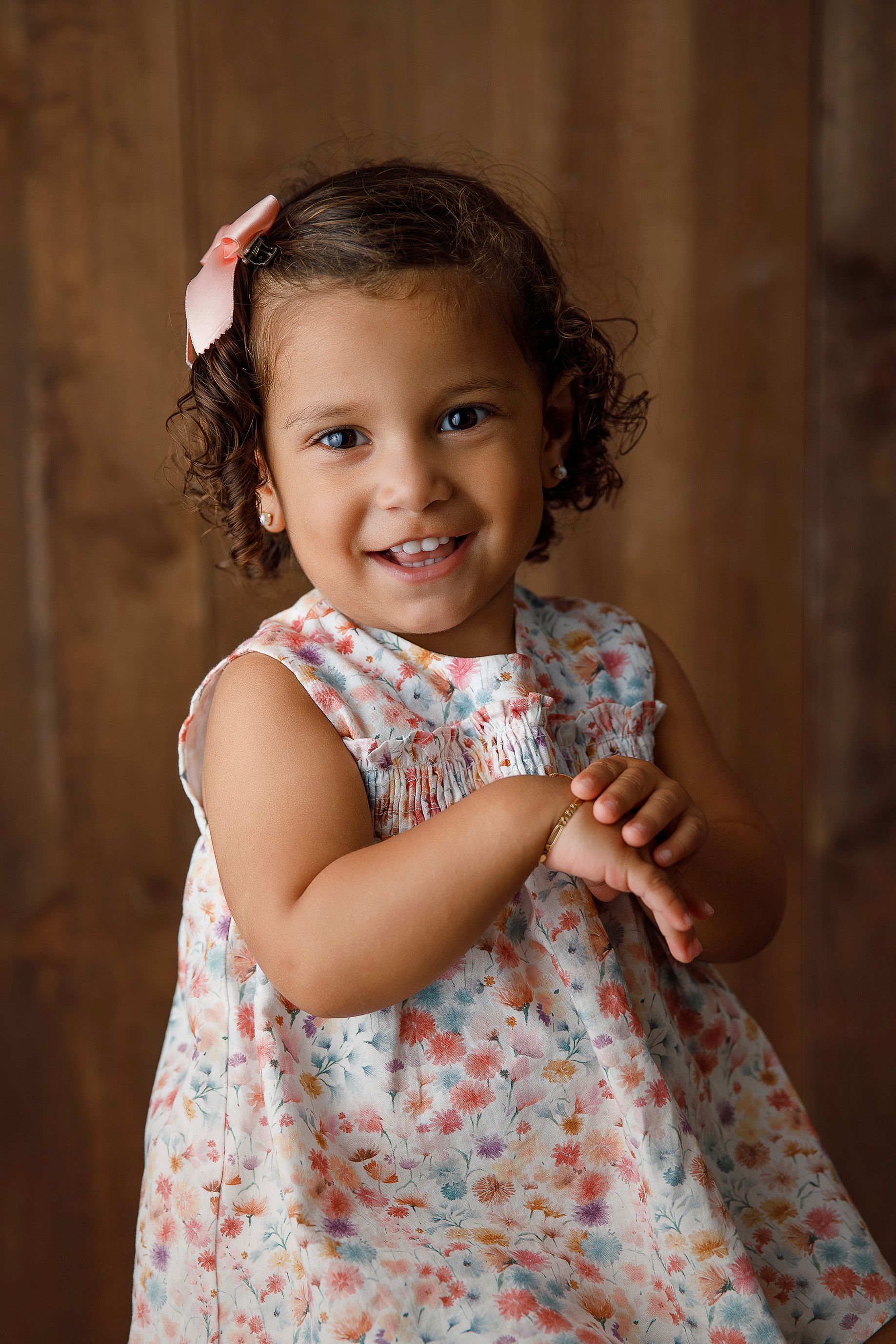 Una niña con un vestido floral sonríe para la cámara.