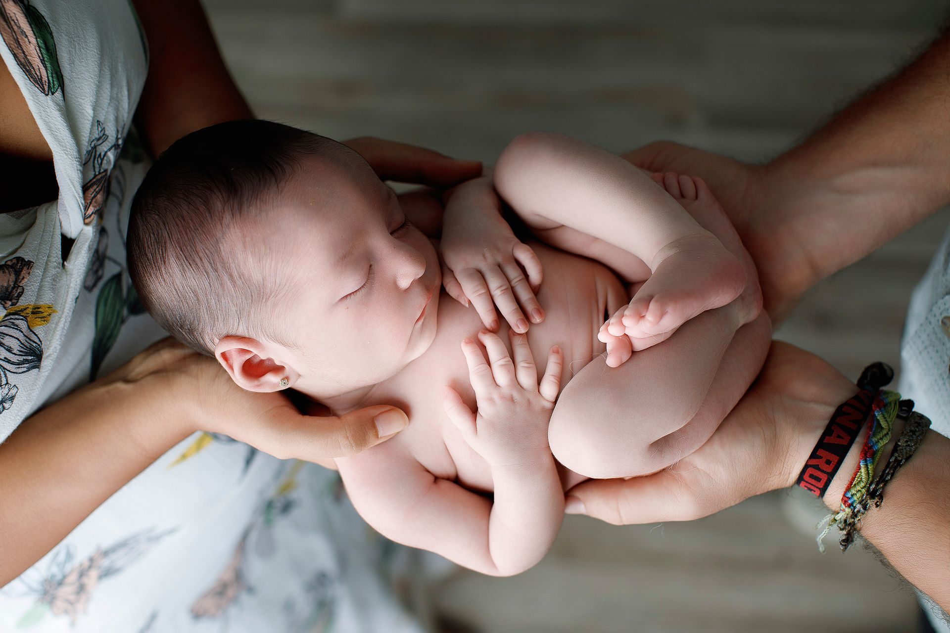 Un hombre y una mujer sostienen un bebé recién nacido en sus brazos.