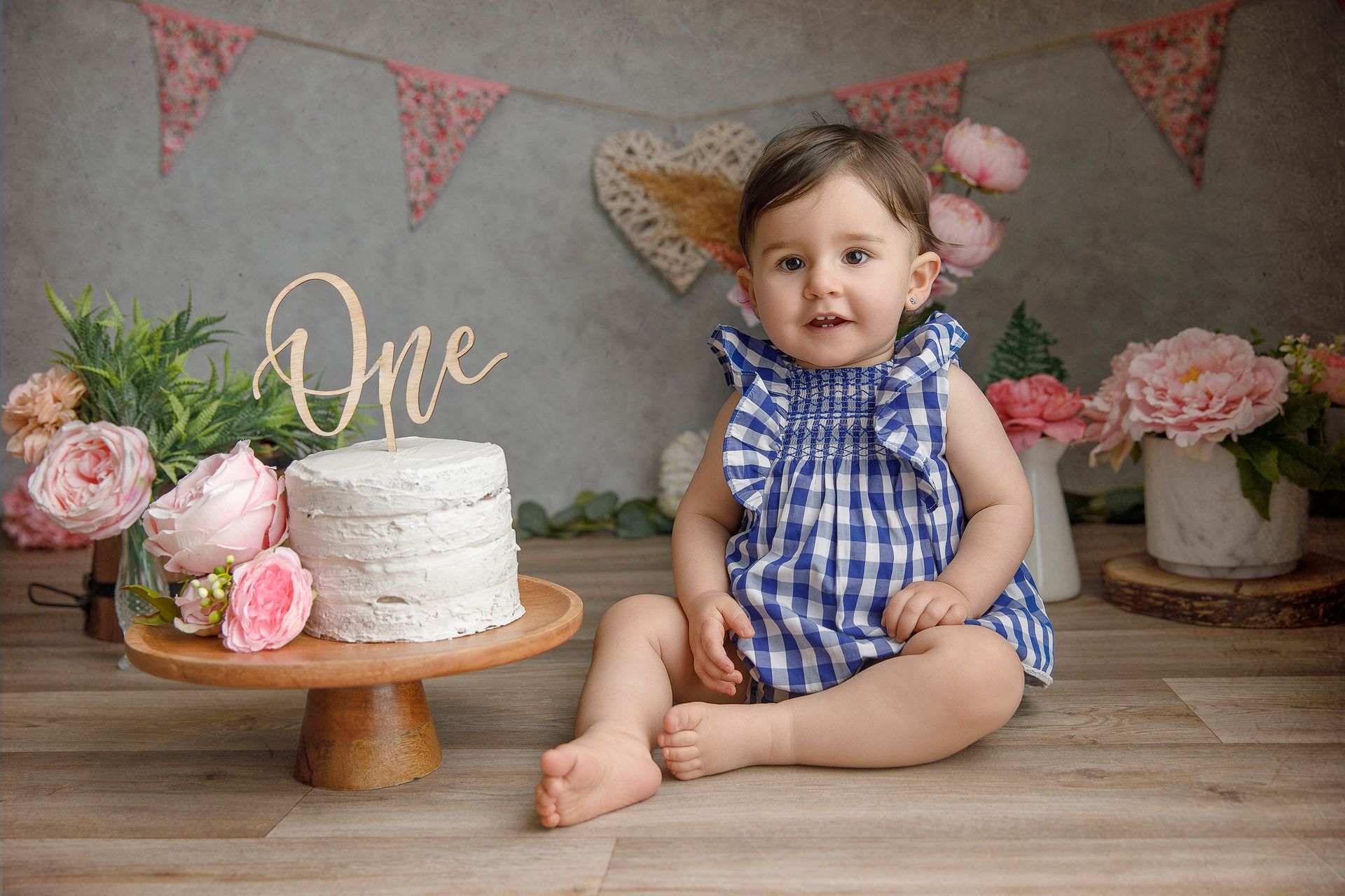 Una niña está sentada en el suelo delante de un pastel.