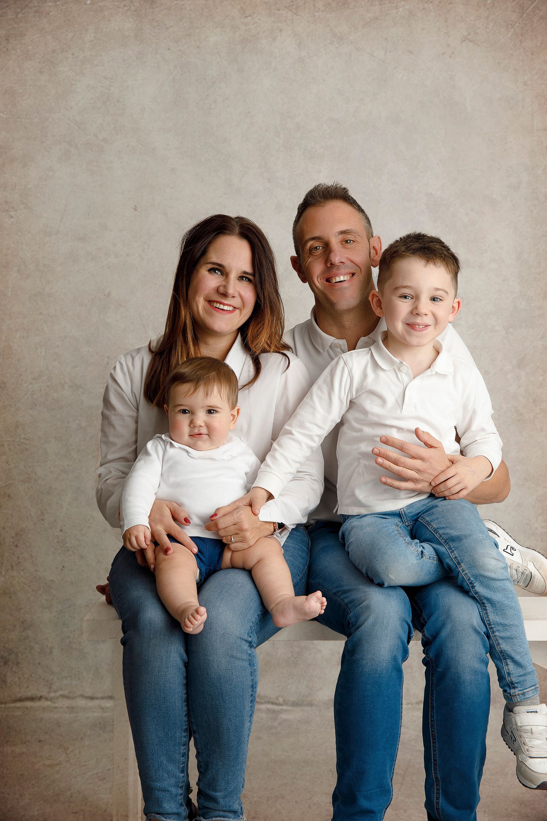 Una familia posa para una fotografía mientras está sentada en un banco.