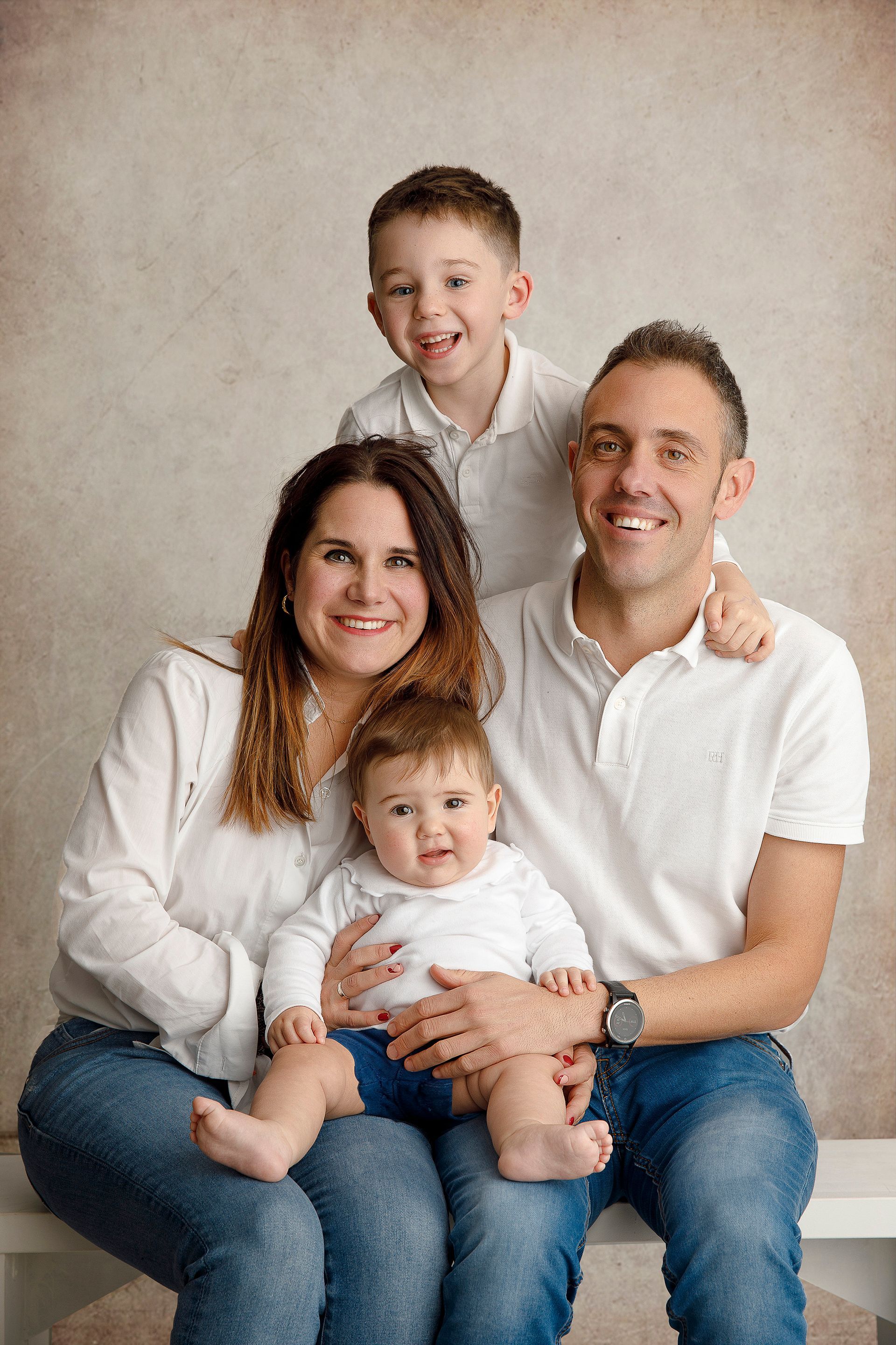 Una familia posa para una fotografía mientras está sentada en un banco.