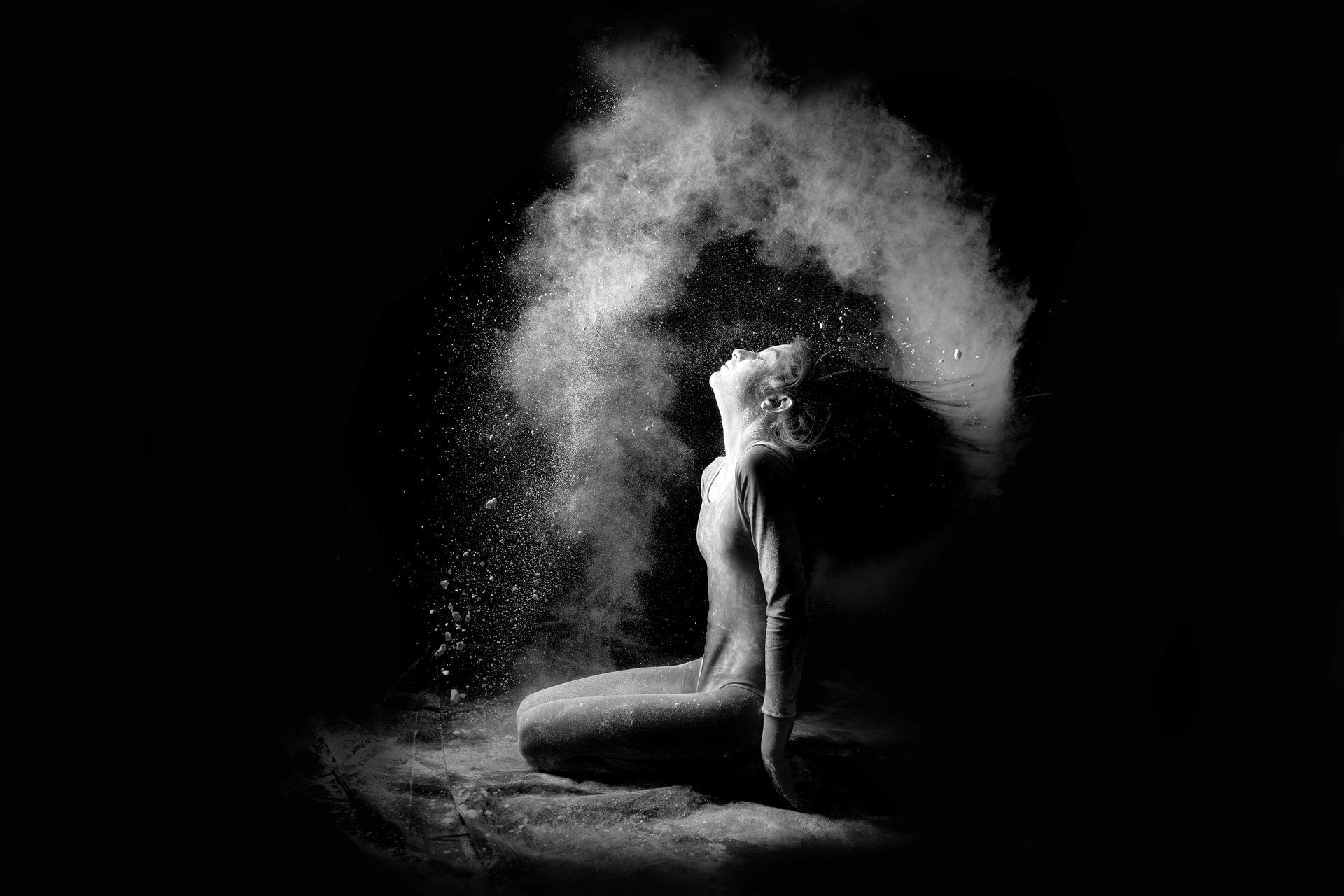 Una fotografía en blanco y negro de una mujer sentada frente a una nube de polvo.
