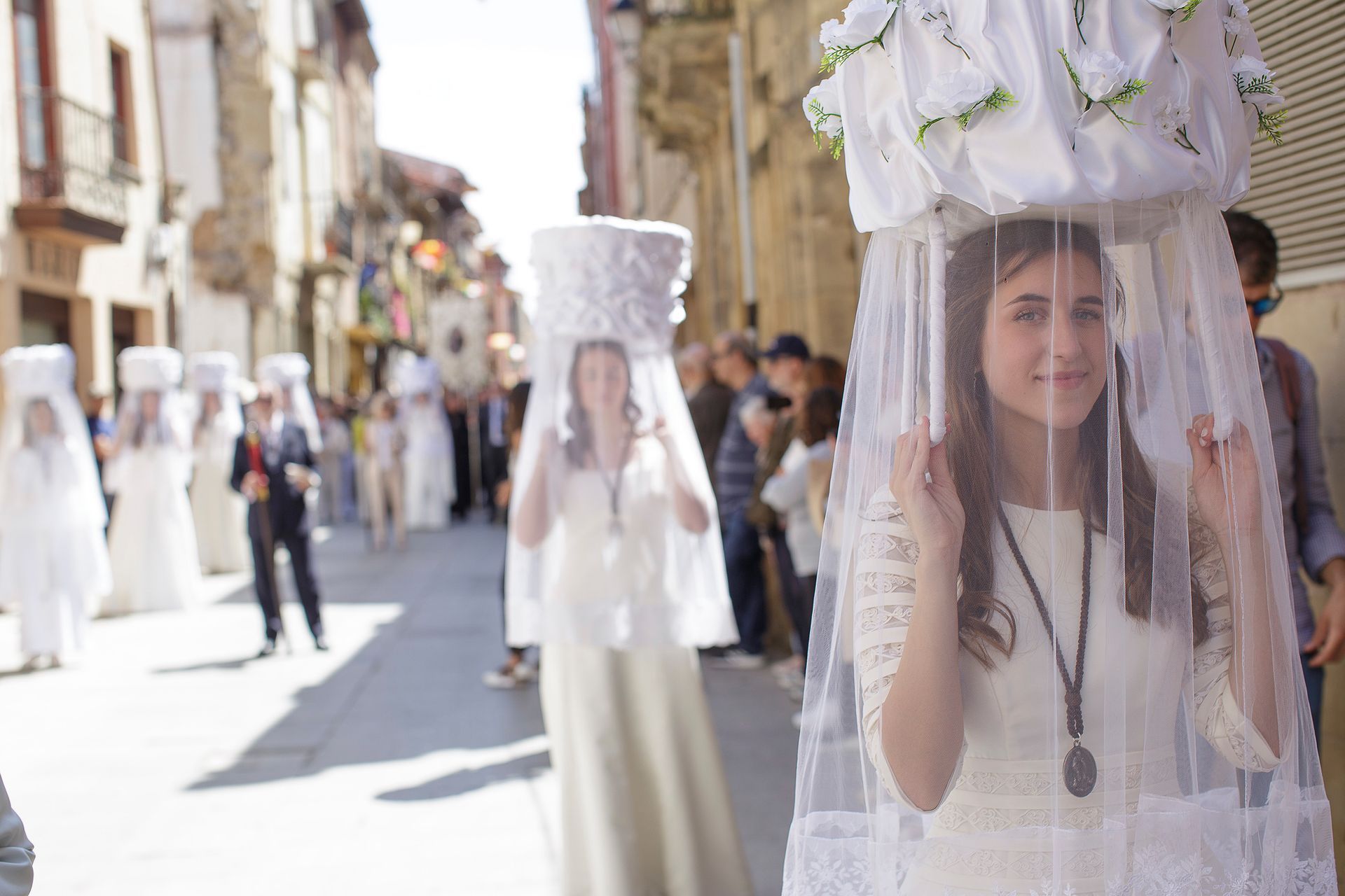 Una mujer con un vestido blanco y un velo camina por una calle.