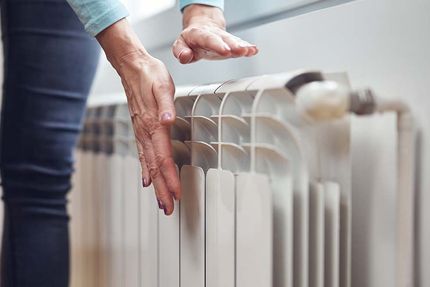 Une femme approche ses mains d'un radiateur