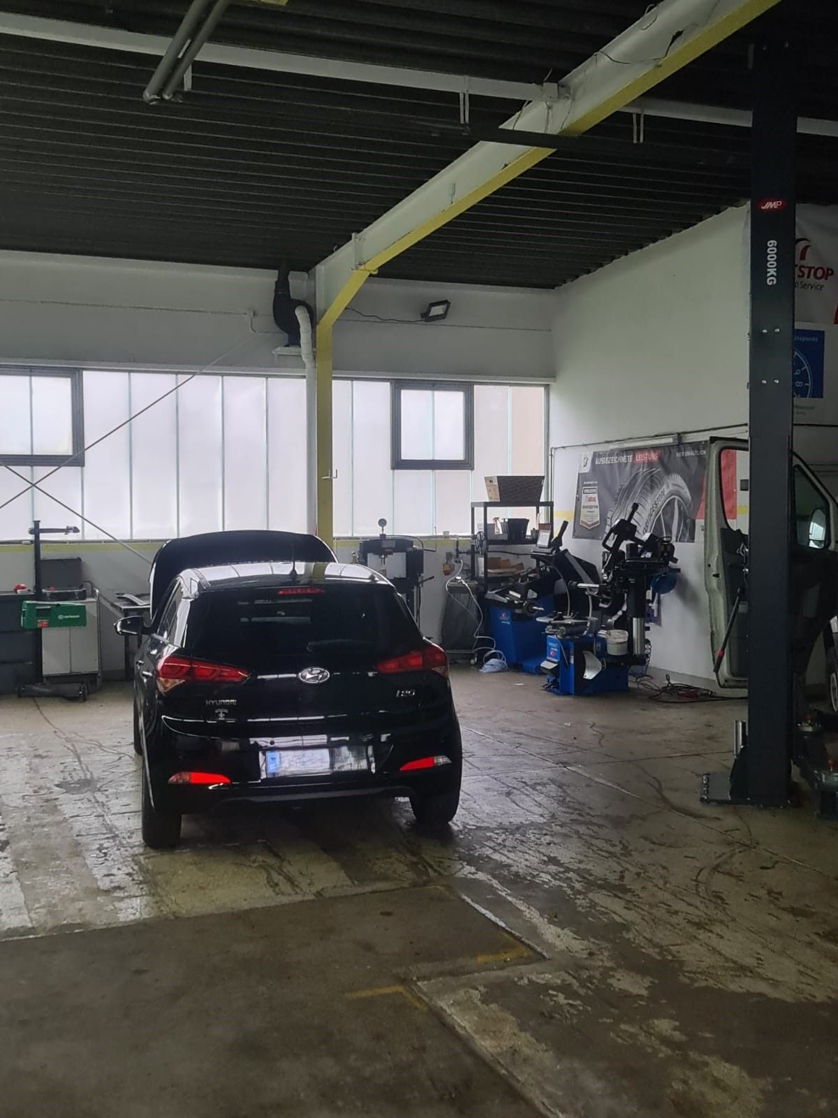 Ein schwarzes Auto steht in einer Garage neben einem Motorrad.