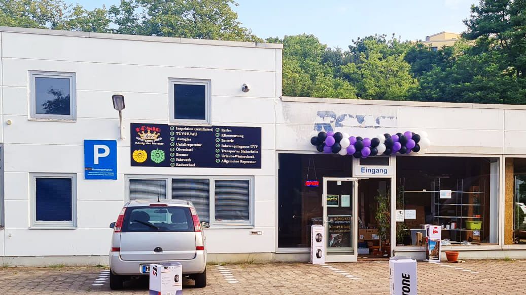 Ein weißes Gebäude mit einem davor geparkten Auto.