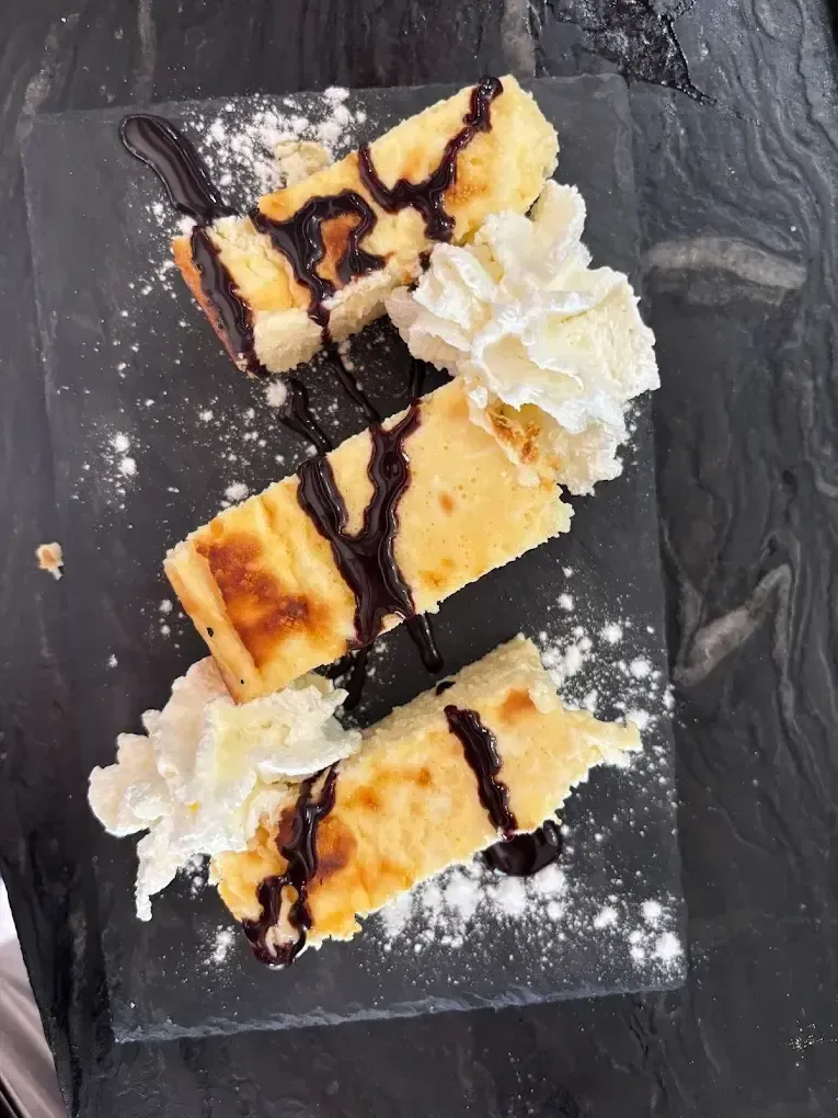 Tres rebanadas de tarta de queso rociadas con salsa de chocolate y adornadas con crema batida