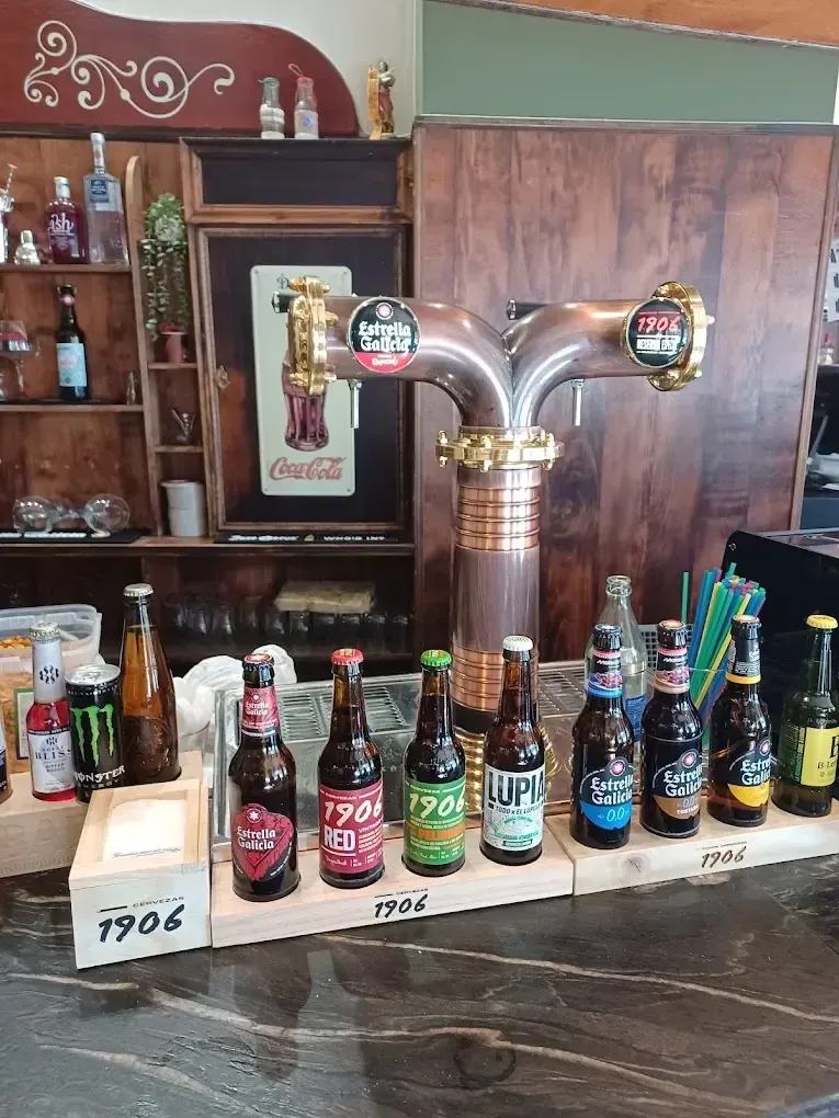 Un mostrador de bar con un grifo de cerveza metálico y una fila de varias botellas de cerveza dispuestas