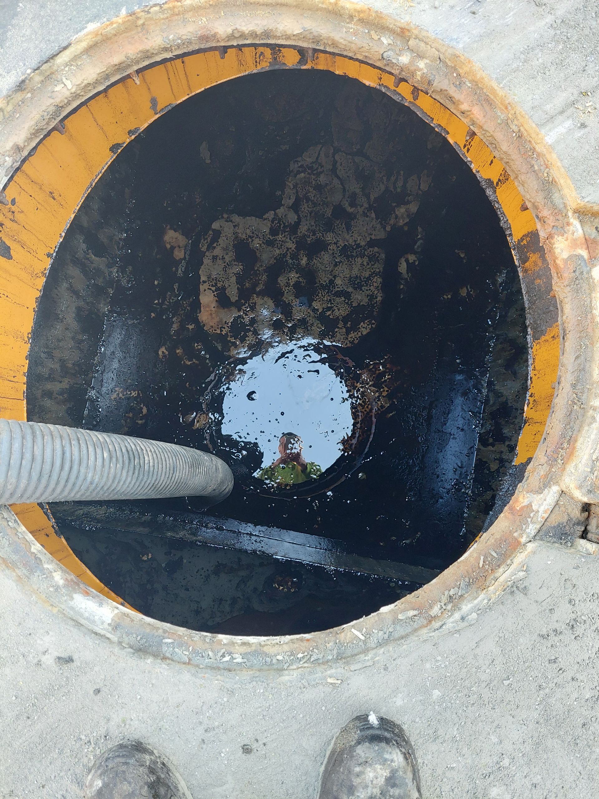 Vue du haut d'un regard de fosse septique ouvert avec un tuyau dedans