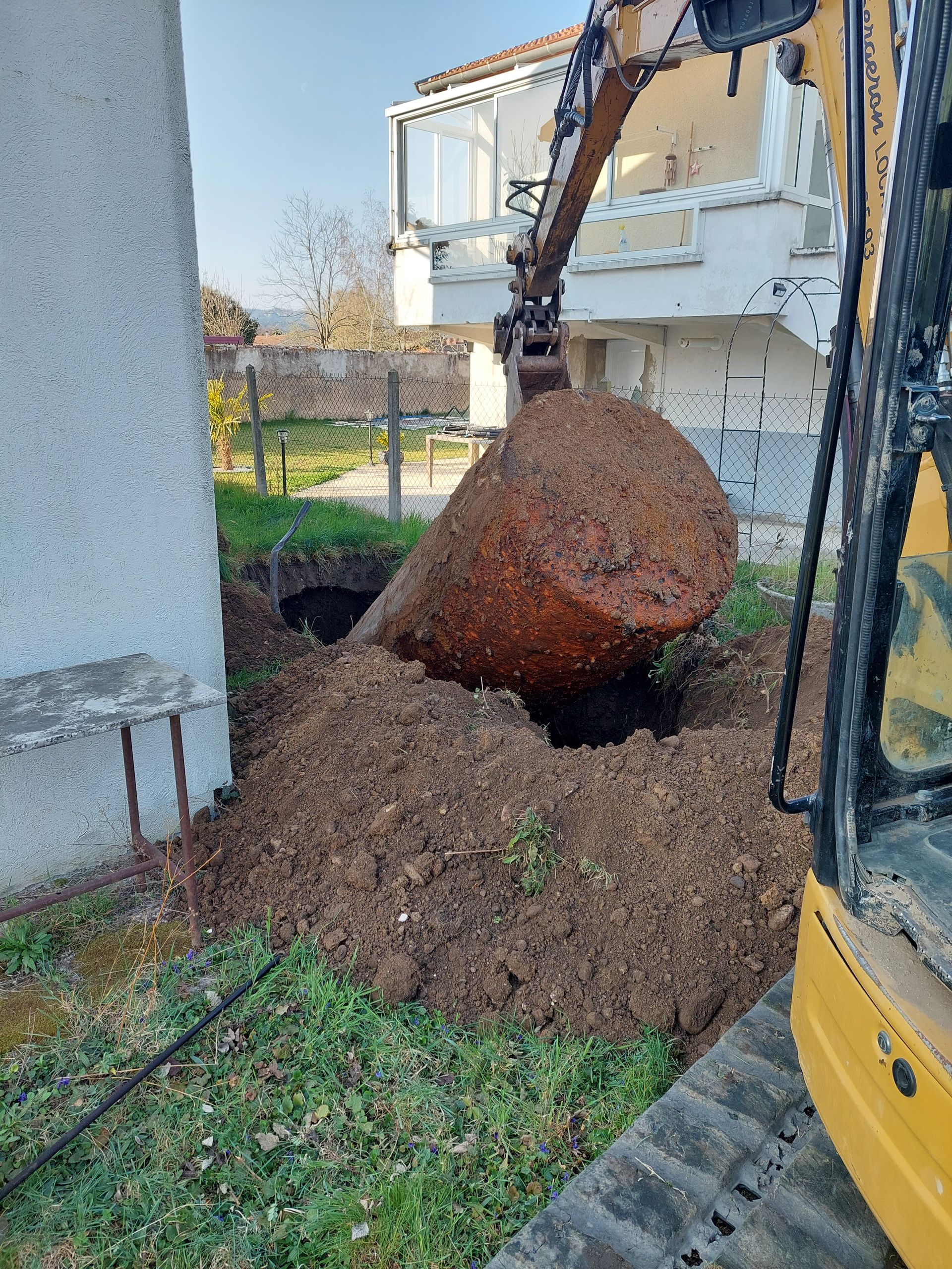 Un employé enlève une cuve à fioul du sol où elle était enterrée