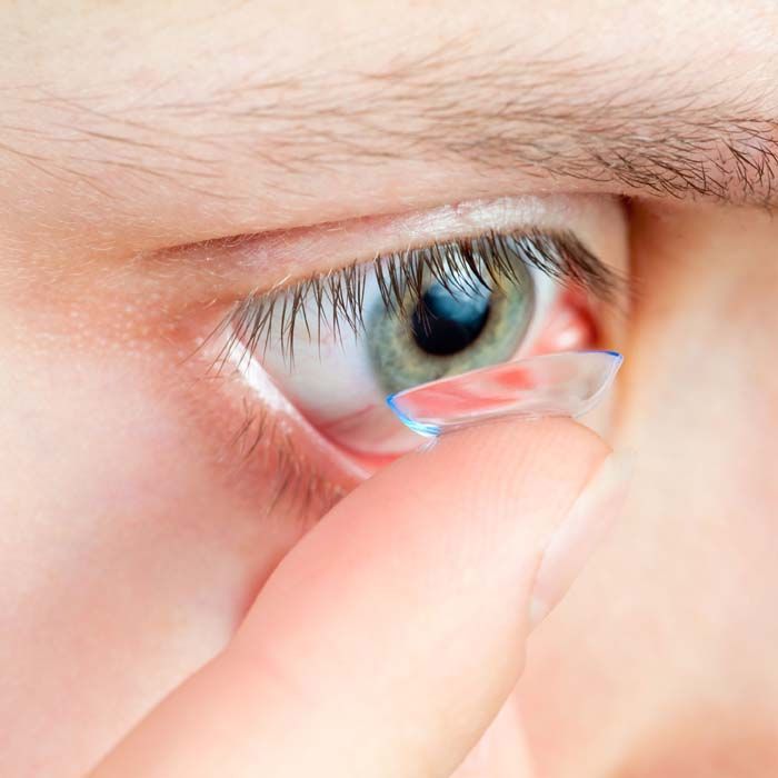 Un primer plano de una persona colocándose una lente de contacto en el ojo.