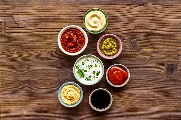 Una mesa de madera cubierta con cuencos de diferentes salsas.