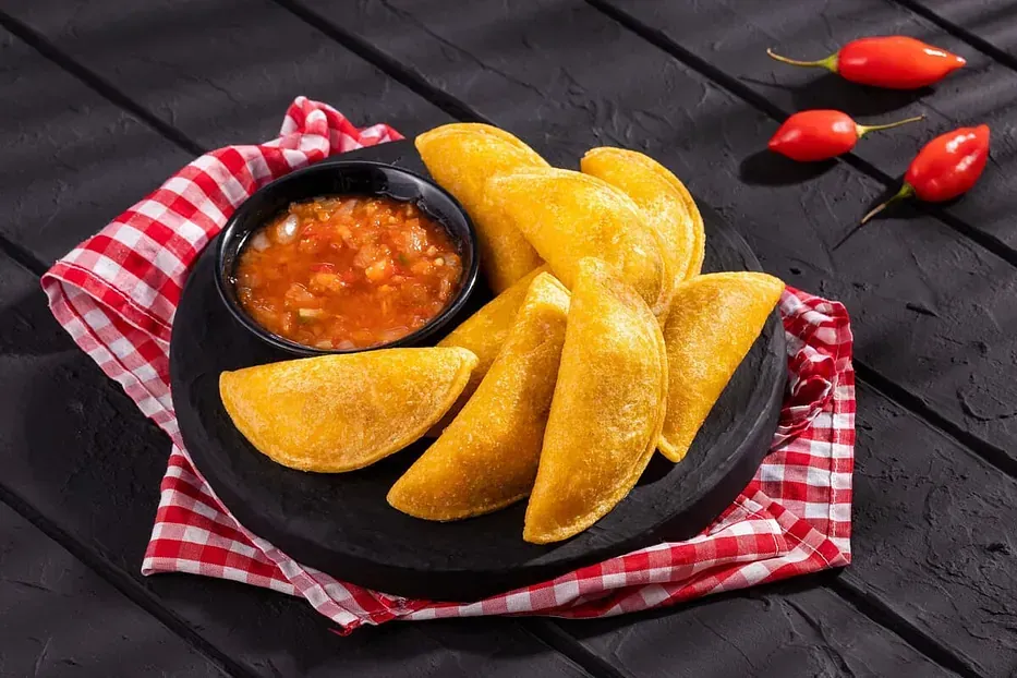 Un plato de comida con un tazón de salsa sobre una mesa de madera.