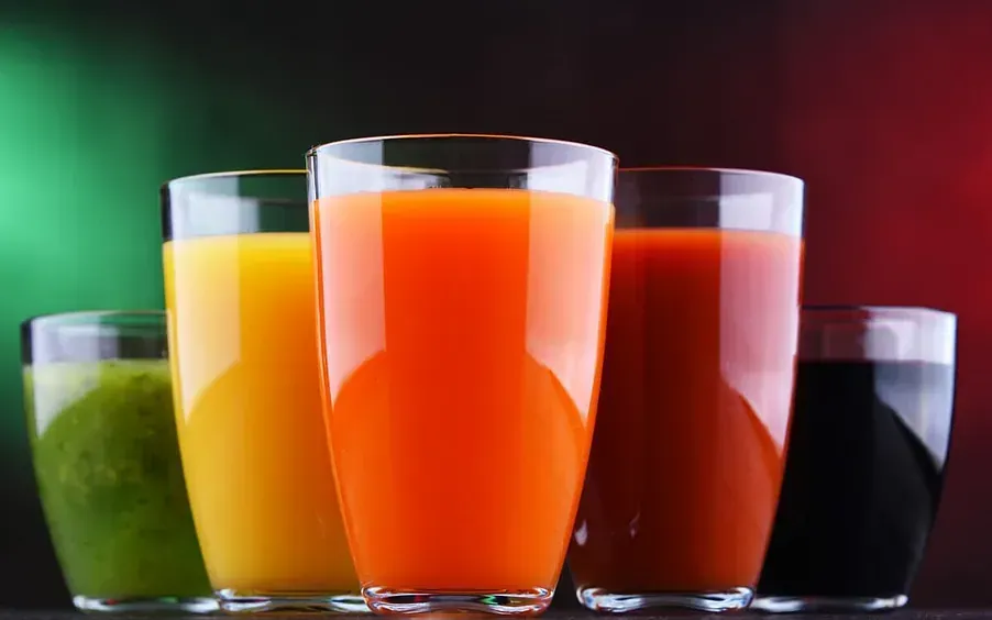 Una fila de vasos llenos de diferentes tipos de jugos.