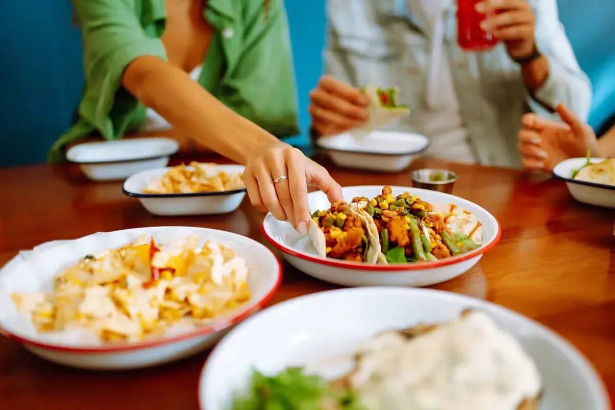 Un grupo de personas está sentada en una mesa comiendo comida.