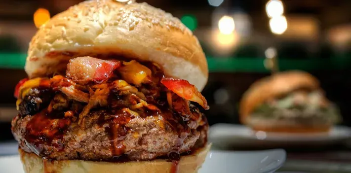 Un primer plano de una hamburguesa en un plato sobre una mesa.