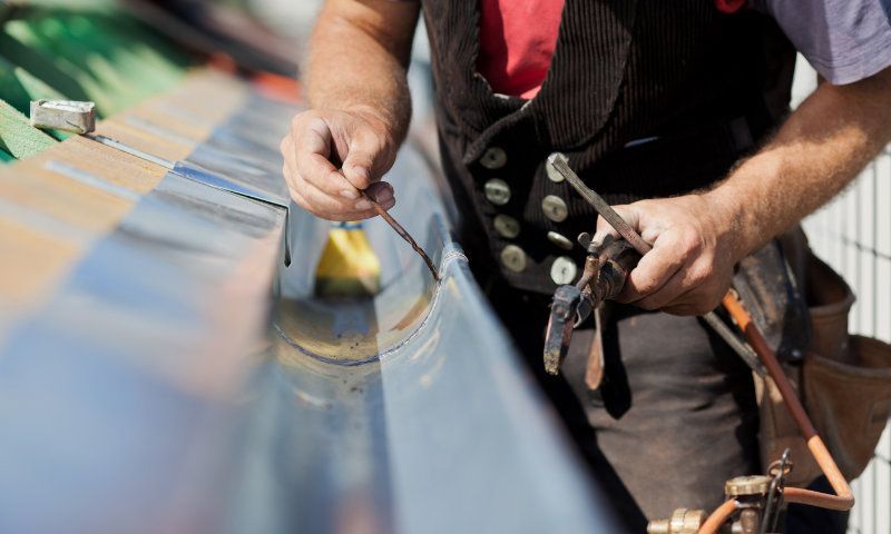 Dachdecker verlötet die Regenrinne