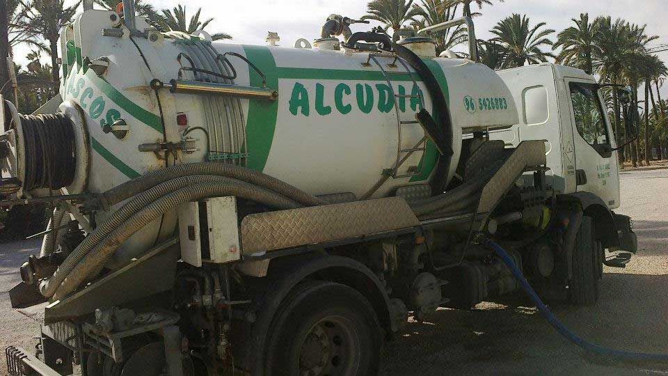 Un camión blanco y verde de Alcudia está estacionado al costado de la carretera.