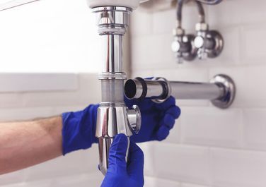 Un fontanero está arreglando una tubería del fregadero de un baño.