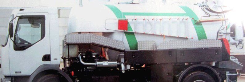 Un camión blanco con rayas verdes y rojas en los costados está estacionado frente a un edificio.