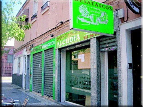 Un escaparate con un cartel verde que dice Alcudia.