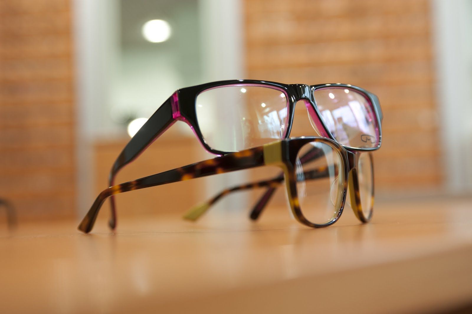 Auf einem Tisch sind zwei Brillen übereinander gestapelt.