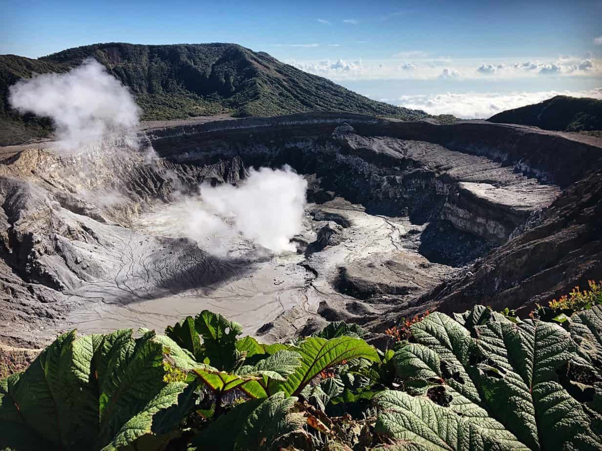 A view of Poas volcano with steam coming out of it.