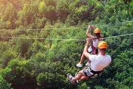 A man and a woman are flying through the air on a zip line.