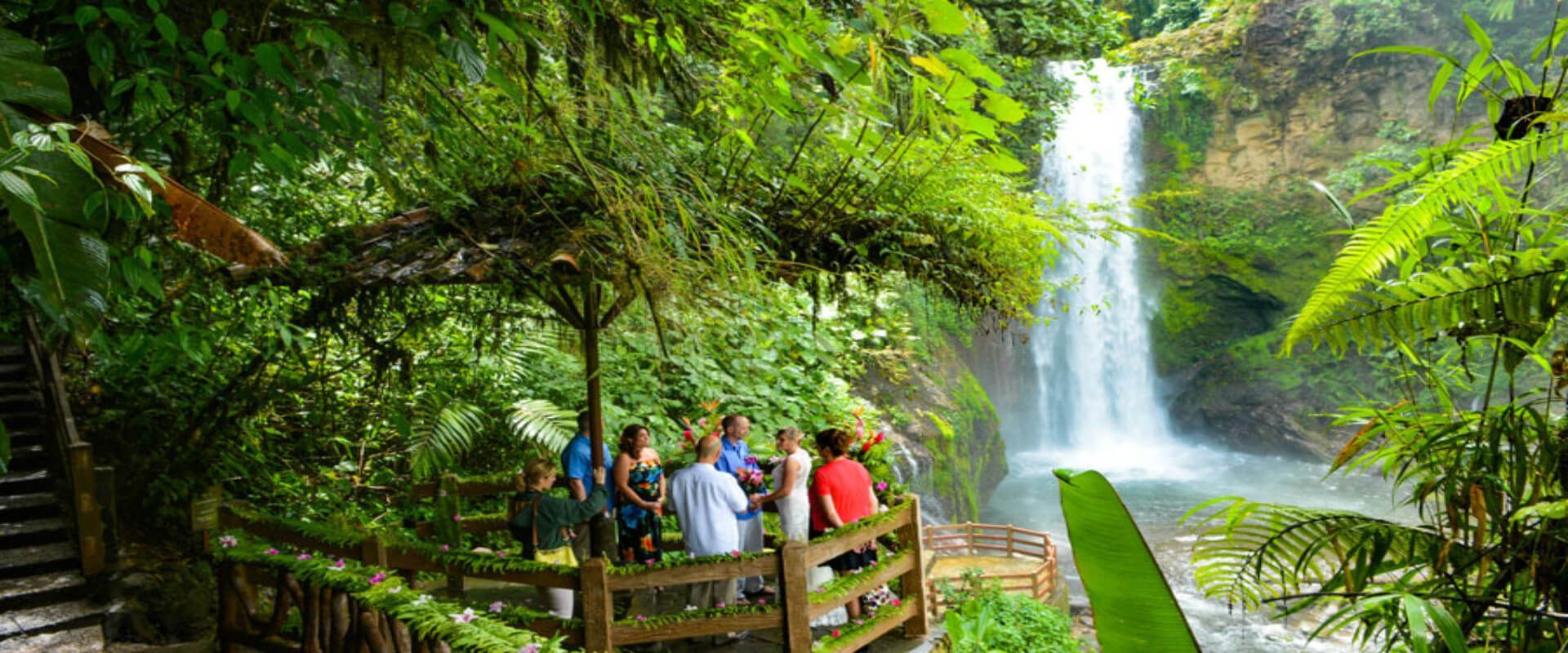 A group of people are looking at a waterfall at La Paz Waterfall Gardens