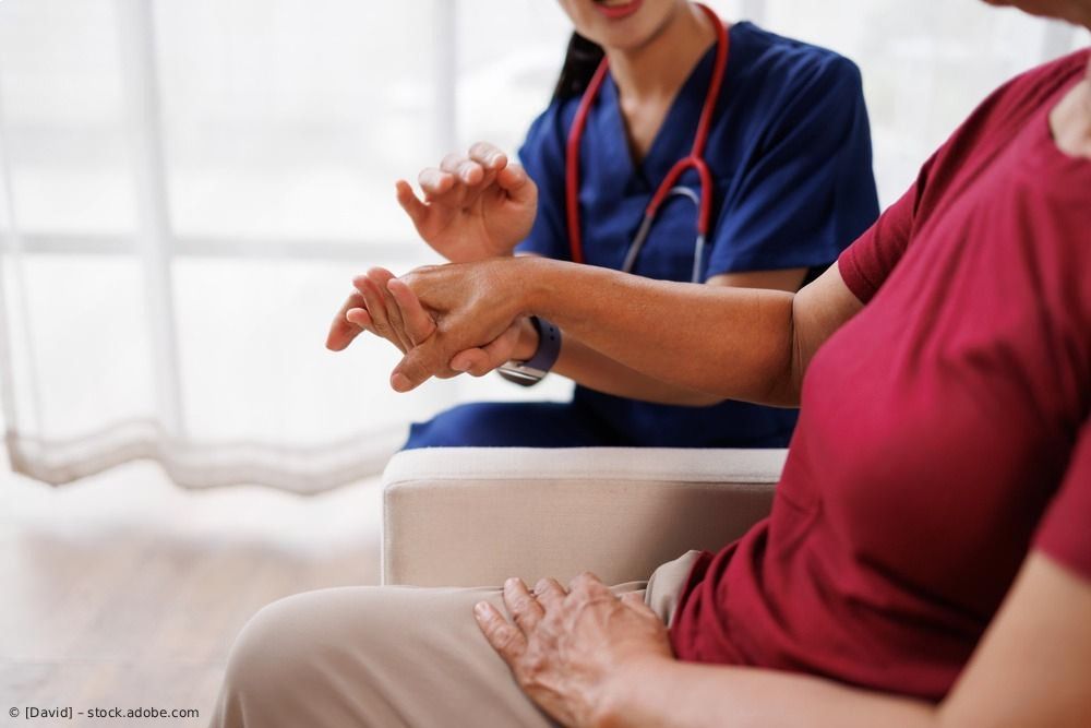 Therapeut leitet einen Patienten in einem Behandlungsraum durch Handübungen.